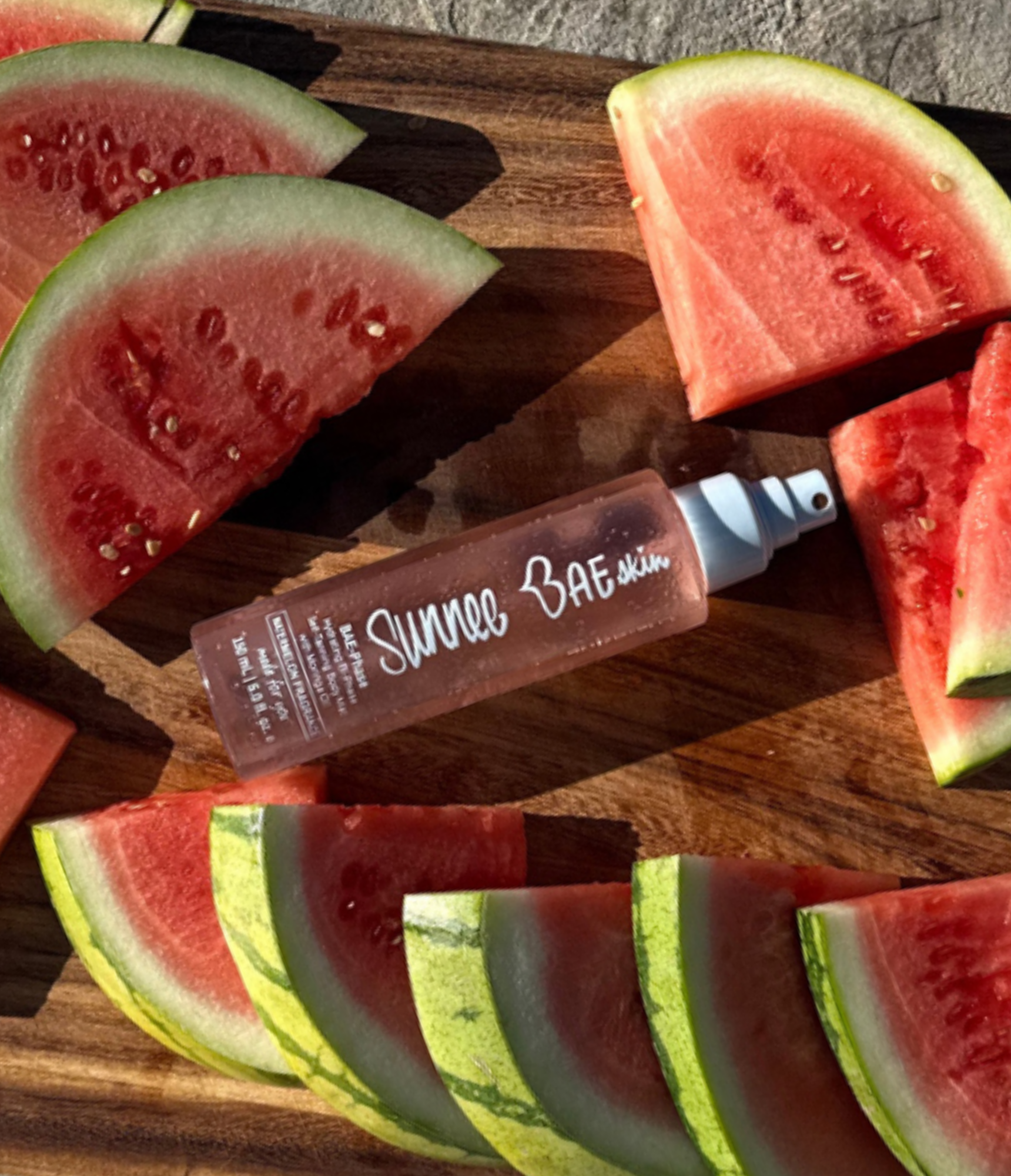 Sunnee Bae watermelon BAE-phase body mist product on a wooden cutting board with watermelon slices