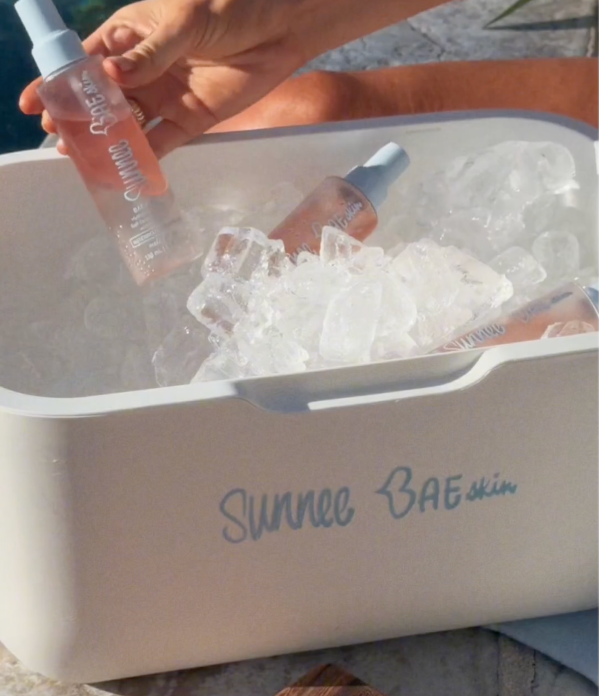 White Sunnee BAEskin cooler filled with ice and Watermelon BAE Phase Body Mist bottles
